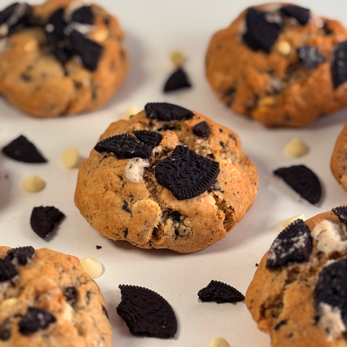 Oreo-infused chocolate chip cookies with crushed dark cookie pieces and white chocolate chips, arranged on a white surface.